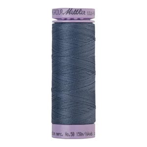 May include: A spool of dark blue thread with a purple label that reads "GROUP - Mettler SILK-F-100 No. 50 150m/164yds".