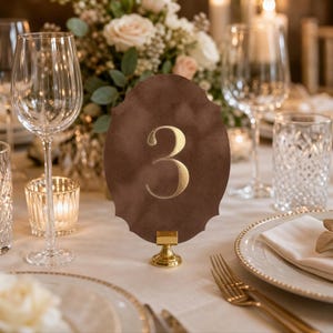 a table setting with a brown oval-shaped table number holder displaying the number 3, surrounded by various glassware, plates, and silverware.