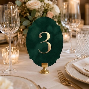 A table setting with a green oval table number holder displaying the number 3, surrounded by wine glasses, plates, and other tableware.