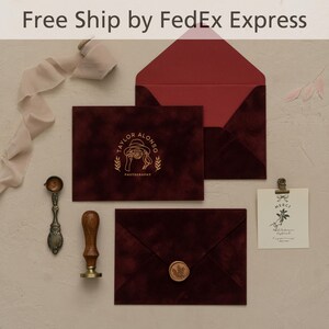 May include: Burgundy velvet stationery set with a gold foil logo and wax seal. Includes envelopes, cards, a wax stamp, and a small card with a floral illustration. The text "TAYLOR ALONSO PHOTOGRAPHY" is visible.