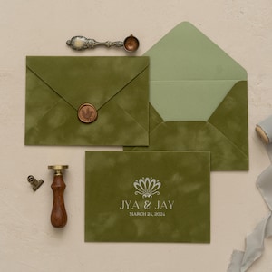 a green envelope with a wax seal, a wooden clip, and a ribbon, all arranged on a light-colored surface.