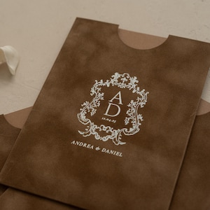 A brown paper bag with a white crest design and text printed on it.