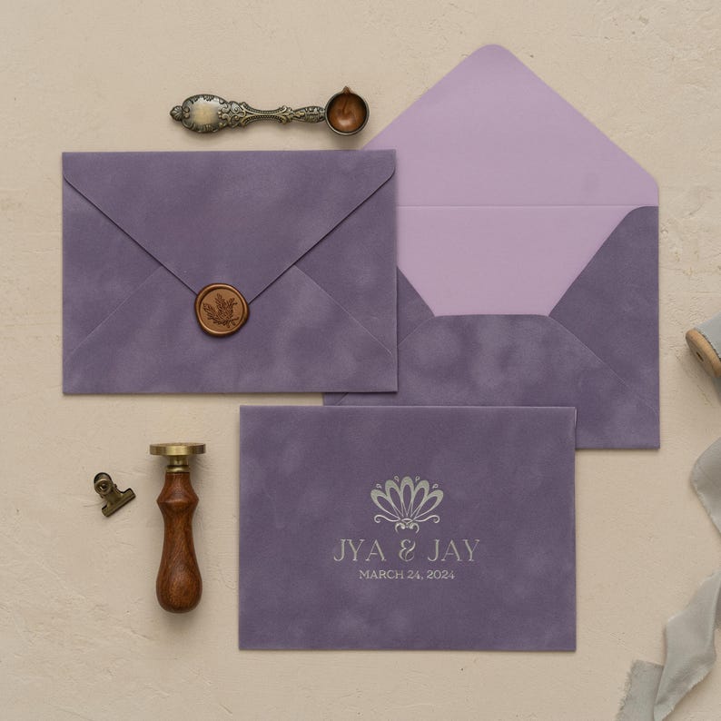 a collection of purple envelopes, a wooden seal, and a wax seal, all arranged on a light-colored surface.