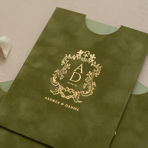 A close-up of a green envelope with a gold embossed monogram and text on it.