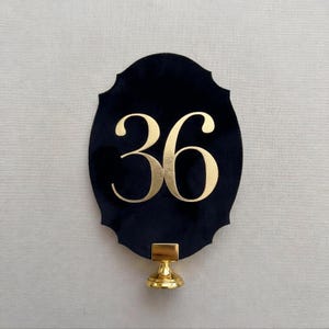 a black oval-shaped sign with the number 36 prominently displayed in gold lettering.