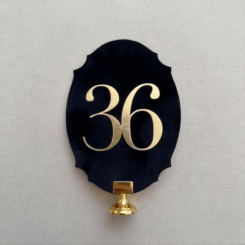 a black oval-shaped sign with the number 36 prominently displayed in gold lettering.
