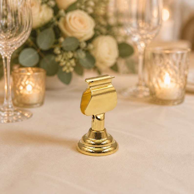a gold-colored paperweight or binder clip on a table, surrounded by various glassware and floral arrangements.