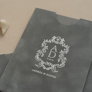 A gray folder or envelope with a white decorative crest and text printed on it.