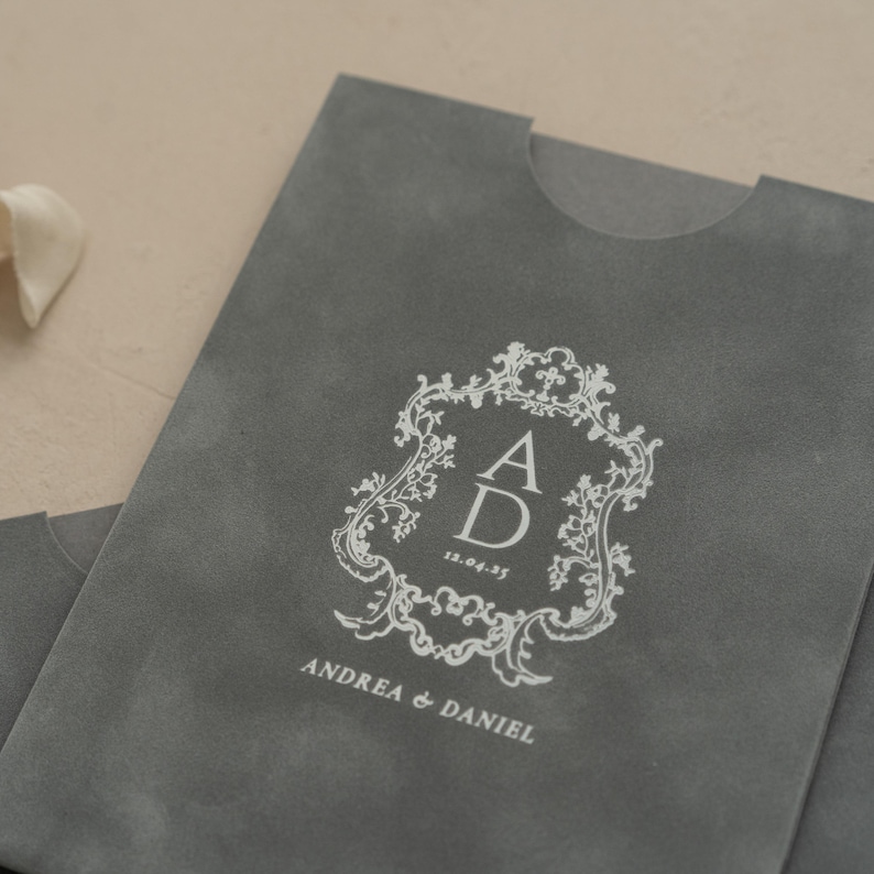A gray folder or envelope with a white decorative crest and text printed on it.