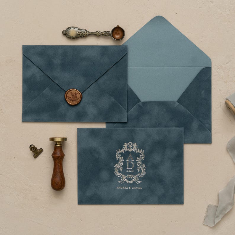 a collection of items related to wedding invitations, including envelopes, a wax seal, a wooden seal, and a ribbon.