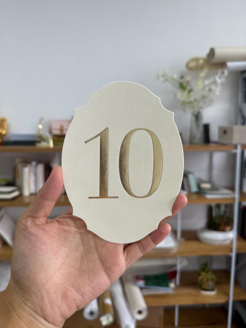 A hand is holding a white oval-shaped object with the number "10" printed on it.