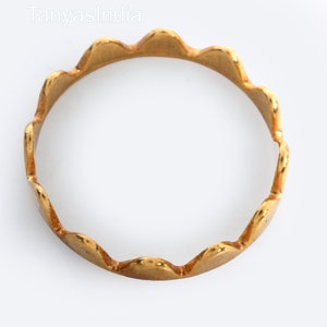 May include: A gold ring with a scalloped edge. The ring is simple and elegant.
