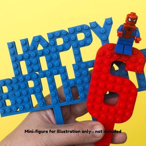 May include: Blue and red Lego-style cake toppers that spell out "Happy Birthday" with a red number six.