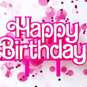May include: A pink and white "Happy Birthday" cake topper with a decorative font. The topper is surrounded by pink confetti on a white background, creating a festive and celebratory atmosphere.