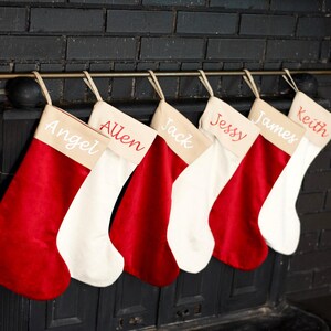 A row of five personalized Christmas stockings hanging on a black brick wall.