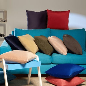 May include: A turquoise sofa with a variety of throw pillows in different colors and textures, including navy blue, beige, brown, red, and green.