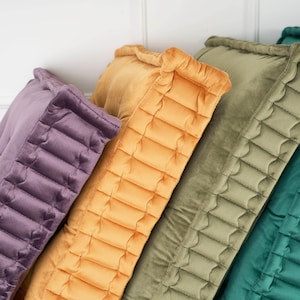 Puede incluir: Cuatro almohadas decorativas con un dise&ntilde;o acolchado. Las almohadas son en tonos de morado, amarillo, verde y turquesa.