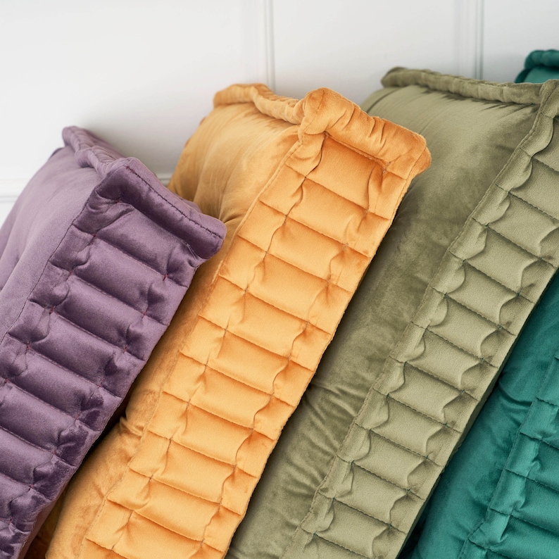 Puede incluir: Cuatro almohadas decorativas con un dise&ntilde;o acolchado. Las almohadas son en tonos de morado, amarillo, verde y turquesa.