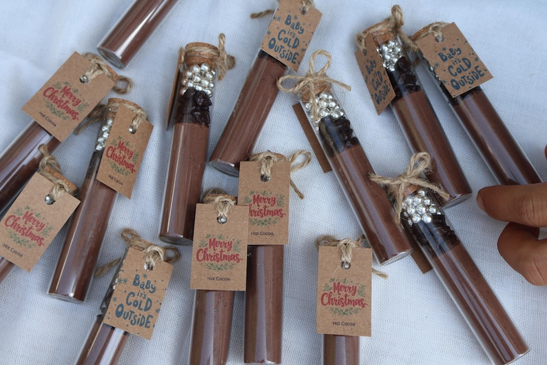 May include: Clear glass tubes filled with brown powder, some with decorative silver beads and cork stoppers. Each tube has a small brown tag with the words "Merry Christmas" or "Baby it's Cold Outside".