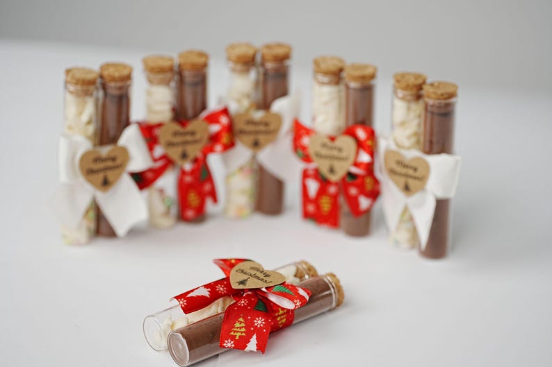 May include: A set of small glass tubes tied with red and white ribbon, each containing a white and brown powder. The tubes are decorated with a heart-shaped tag that says "Merry Christmas".