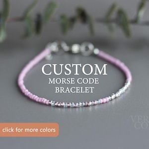May include: A pink and silver beaded bracelet with a silver clasp. The bracelet is labelled "CUSTOM MORSE CODE BRACELET".