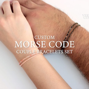 Könnte beinhalten: Ein Set aus zwei personalisierten Morsecode-Armbändern. Das Armband links ist rosa und weiß, während das Armband rechts schwarz und braun ist. Die Armbänder sind um die Handgelenke von zwei Personen gebunden. Der Text "CUSTOM MORSE CODE COUPLE BRACELETS SET" wird in der Mitte des Bildes angezeigt.