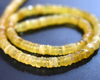 May include: A strand of yellow opal beads. The beads are small and round, and they are strung on a clear thread.