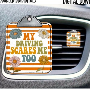 May include: A white car air freshener with orange and white stripes. It has a clipboard design with the text "My Driving Scares Me Too" and a floral design.