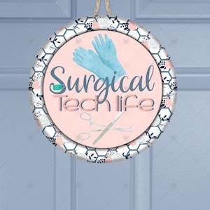 May include: A pink and white round sign with a floral pattern and the text "Surgical Tech Life". The sign also features a pair of blue surgical gloves and surgical tools.