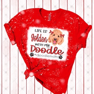 May include: Red t-shirt with a white bleached design featuring a golden doodle dog with a red bow and the text "Life is golden with my doodle #doodlemom".