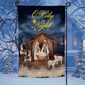 May include: A Christmas garden flag with a nativity scene and the text "O Holy Night". The flag is blue with gold stars and a dark blue sky. The nativity scene is in a wooden stable with a straw roof. There are two donkeys and two sheep in the scene.