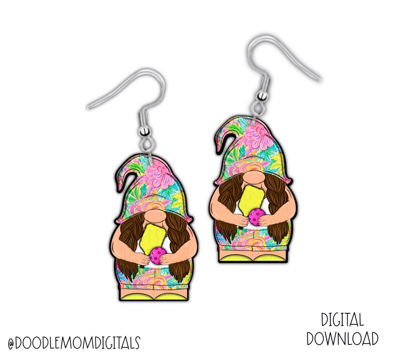 May include: A pair of earrings featuring a gnome holding a yellow popsicle and a purple ball. The gnome is wearing a floral patterned hat and a yellow and pink patterned dress. The earrings are silver.