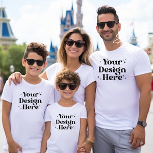 May include: A family of four wearing white t-shirts with the text "Your Design Here" printed on them. They are standing in front of a colourful building with a blue roof.