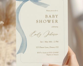 May include: A baby shower invitation with a light blue ribbon and text. The invitation reads "Baby Shower" and includes the name "Emily Johnson", date, time, and address. The invitation is held in a person's hand.