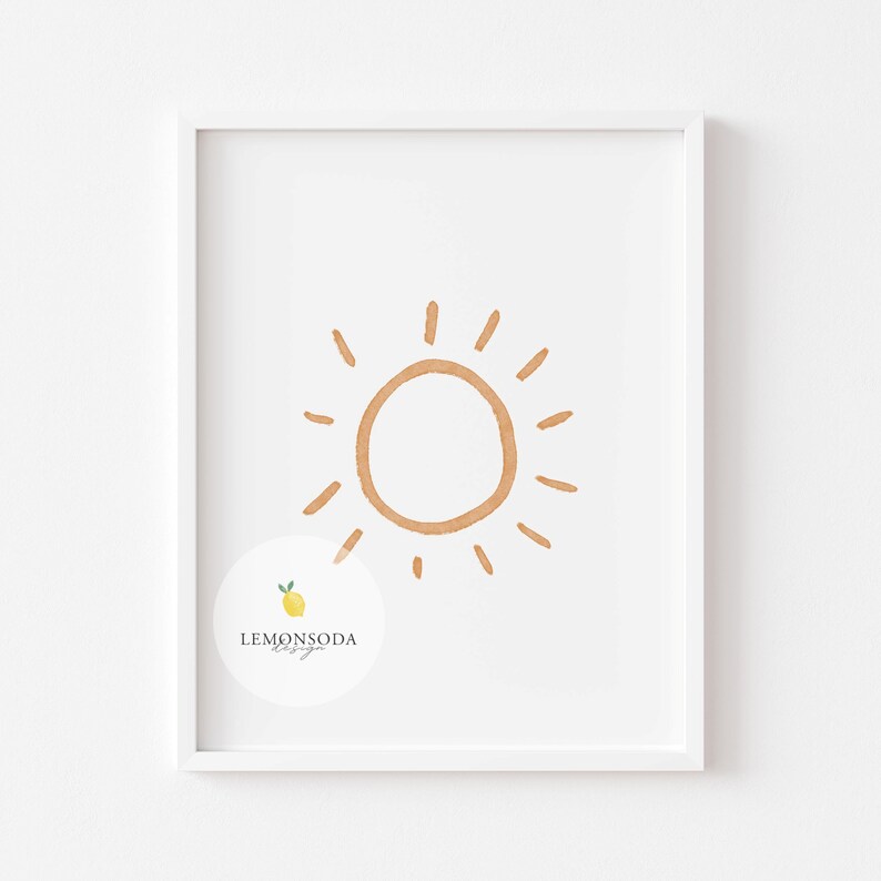 Pu&ograve; includere: Una stampa incorniciata bianca con un semplice sole disegnato a mano in arancione su uno sfondo bianco. La stampa ha un piccolo logo in basso a sinistra che dice "LEMONSODA design".