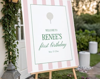 Puede incluir: Un letrero de bienvenida para una fiesta de primer cumpleaños. El letrero presenta rayas rosas y blancas, un borde verde y un gráfico de pelota de golf. El texto dice "Welcome to Renee's first birthday" y la fecha.
