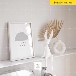 May include: A white framed print with a gray cloud and colorful raindrops. A white bunny figurine sits on a shelf with a vase and dried palm leaves. The text "Lemon Soda Design" is visible in the image.