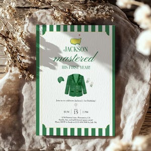 Könnte beinhalten: Eine grüne und weiße Einladungskarte mit dem Text "JACKSON mastered HIS FIRST YEAR!" und Illustrationen zum Thema Golf. Die Karte enthält Eventdetails: Datum, Uhrzeit und Ort für eine erste Geburtstagsfeier.