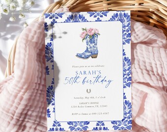 Op de afbeelding: Een witte uitnodiging met een blauwe bloemenrand en een blauwe cowboylaars-illustratie met roze bloemen. De tekst luidt "SARAH'S 50th birthday" met evenementdetails. De uitnodiging ligt op een roze doek.