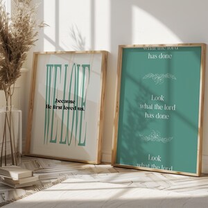 May include: Two framed prints with inspirational quotes. The print on the left has a teal background with the text "We Love because He first loved us." The print on the right has a teal background with the text "Look what the Lord has done. Look what the Lord has done."
