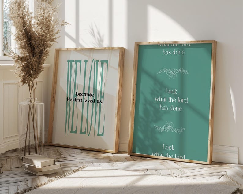 May include: Two framed prints with inspirational quotes. The print on the left has a teal background with the text "We Love because He first loved us." The print on the right has a teal background with the text "Look what the Lord has done. Look what the Lord has done."