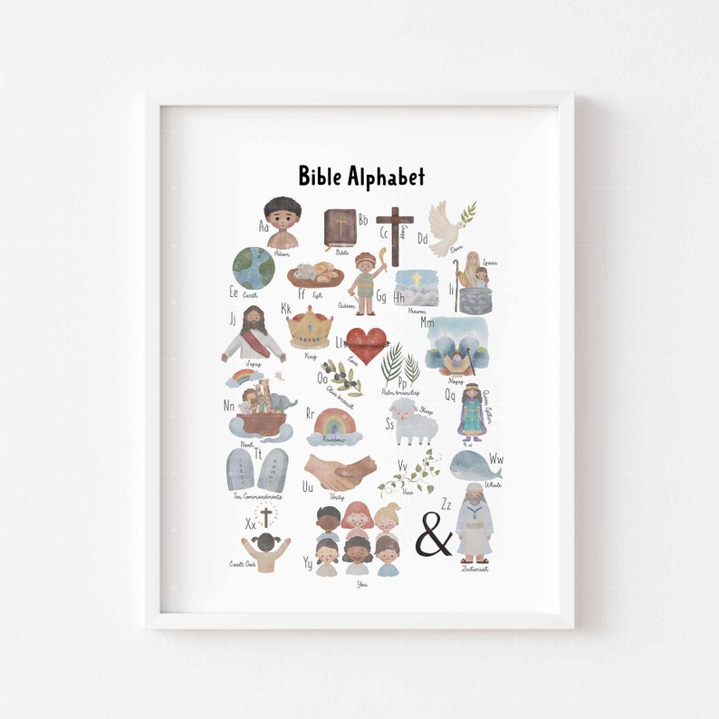 May include: A framed print titled "Bible Alphabet" featuring watercolor illustrations of biblical themes and characters. The artwork includes letters of the alphabet, each paired with a related image, such as a cross, dove, and rainbow. The print is in a white frame.