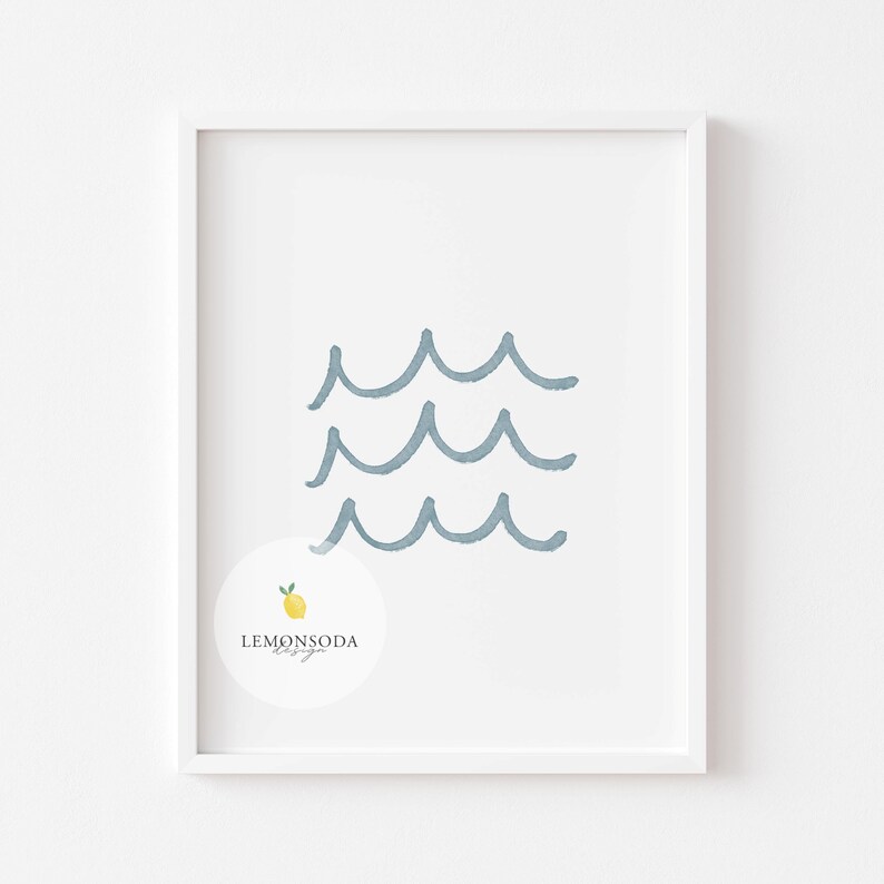 Pu&ograve; includere: Una stampa incorniciata bianca con un design di onde blu in acquerello. La stampa ha un cerchio bianco con un limone giallo e il testo "LEMONSODA Design" in nero.