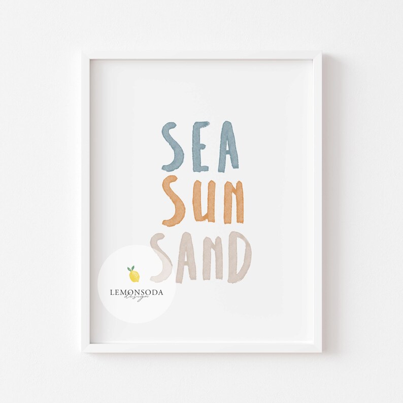 Pu&ograve; includere: Una stampa incorniciata bianca con le parole "SEA SUN SAND" in stile acquerello. Le parole sono in diverse tonalit&agrave; di blu, arancione e marrone. Un piccolo limone con una foglia verde si trova nell'angolo in basso a sinistra.