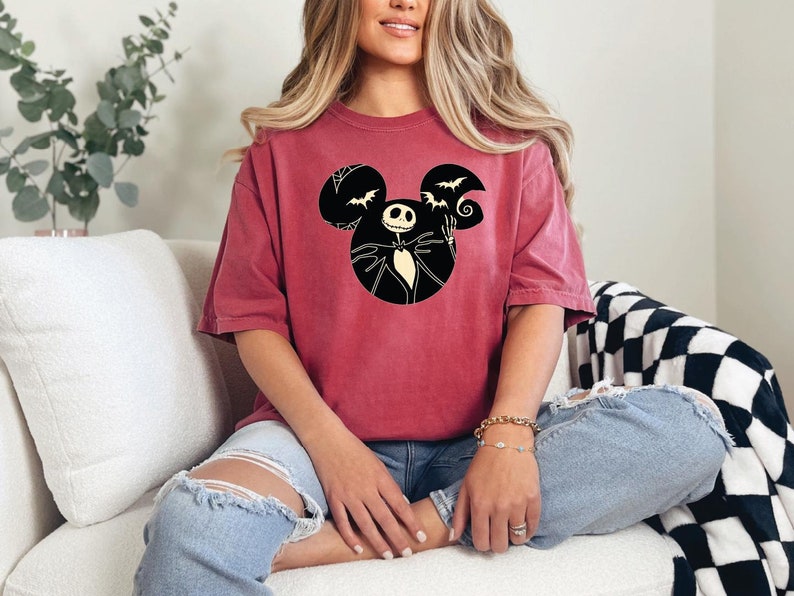 May include: A maroon t-shirt with a black Mickey Mouse silhouette featuring Jack Skellington from The Nightmare Before Christmas.