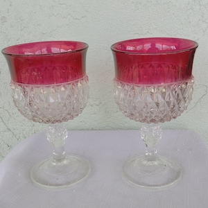 Puede incluir: Dos copas de cristal transparente con tallo, borde rojo rubí y patrón de diamante.