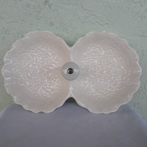 May include: White ceramic serving dish with two sections, shaped like a cabbage leaf. The dish has a raised center knob.
