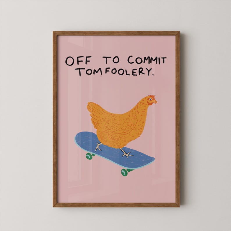 May include: A framed print featuring a cartoon chicken on a blue skateboard against a pink background. The text "OFF TO COMMIT TOMFOOLERY" is written above the chicken. The frame is brown.