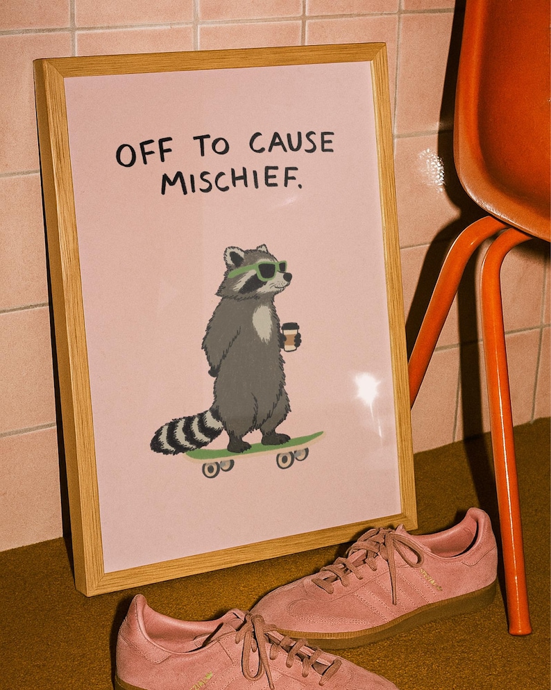 Puede incluir: Un cuadro enmarcado con el texto "OFF TO CAUSE MISCHIEF" muestra un mapache con gafas de sol y una taza de caf&eacute; en un monopat&iacute;n. Zapatillas rosas con suelas marrones en primer plano. El marco es de madera.