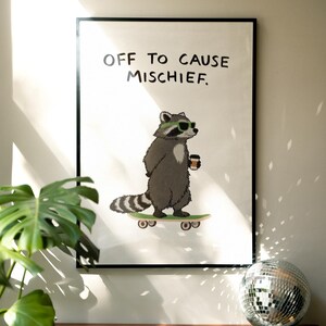 Puede incluir: Una impresi&oacute;n art&iacute;stica enmarcada con un mapache de dibujos animados en monopat&iacute;n, con gafas de sol y una taza de caf&eacute;. La impresi&oacute;n tiene el texto "OFF TO CAUSE MISCHIEF". El mapache es gris y blanco, sobre un fondo blanco.